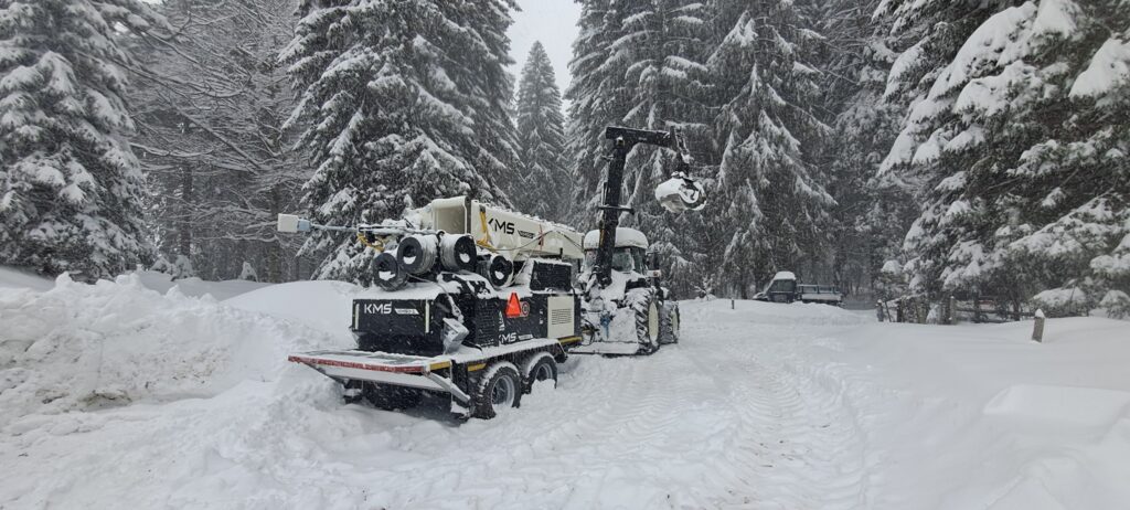 Konrad KMS Kippmast an Traktor angehängt im verschneiten Wald.
